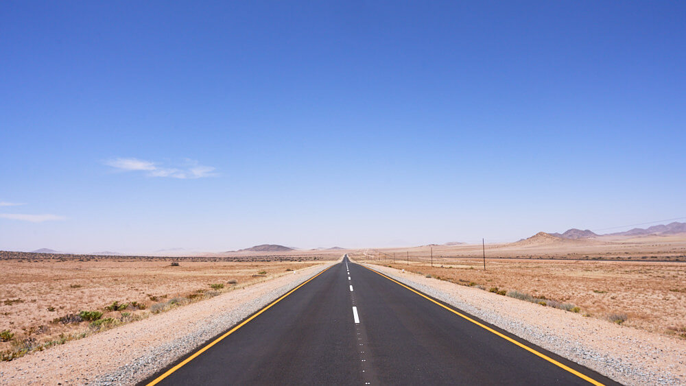 The picture shows an endless tarred road to the horizon.
