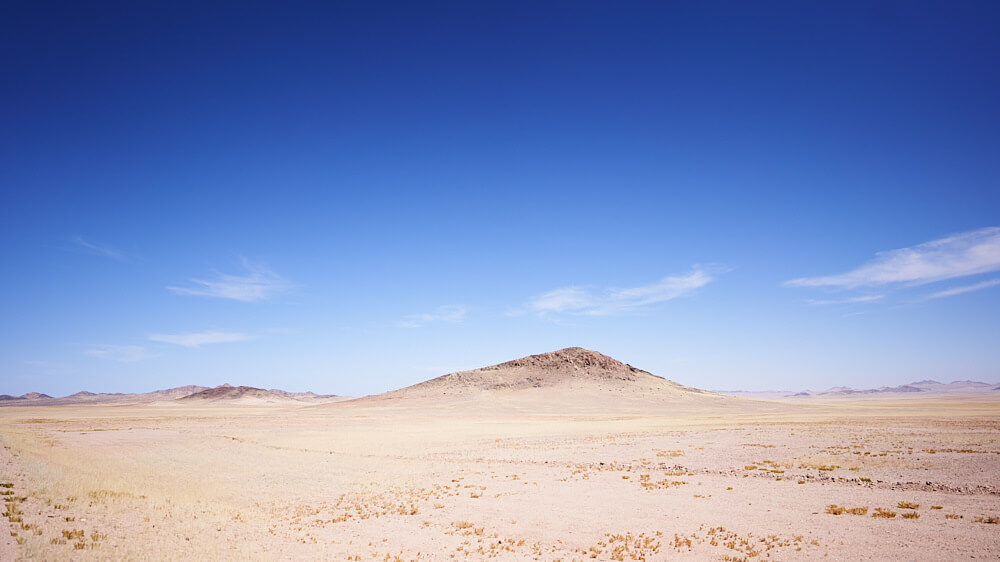 Das Bild zeigt eine Wüstenlandschaft vor blauem Himmel