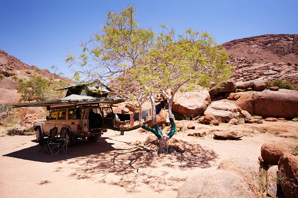 Das Bild zeigt unseren Land Cruiser 76 auf der felsigen Campsite #4 von der Ranch Koiimasis.