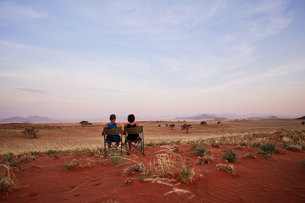 Dieses Bild zeigt ein Paar, dass beim Sundowner in die Weite schaut