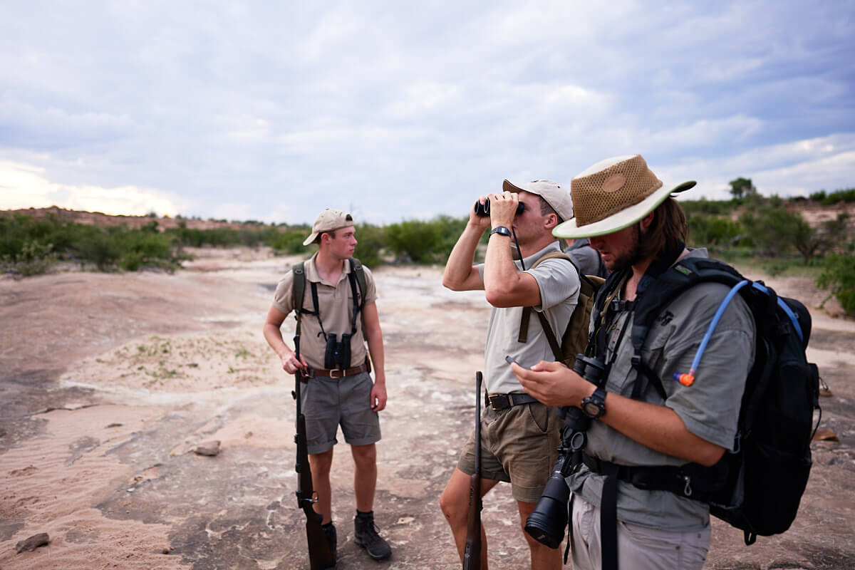 Das Bild zeigt drei Teilnehmer des Trails Guide Kurses, die die Umgebung absuchen.